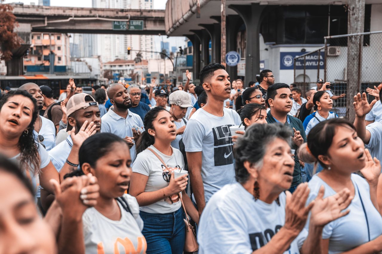 A large group of diverse people gathered outdoors, engaging in a community event in an urban setting.